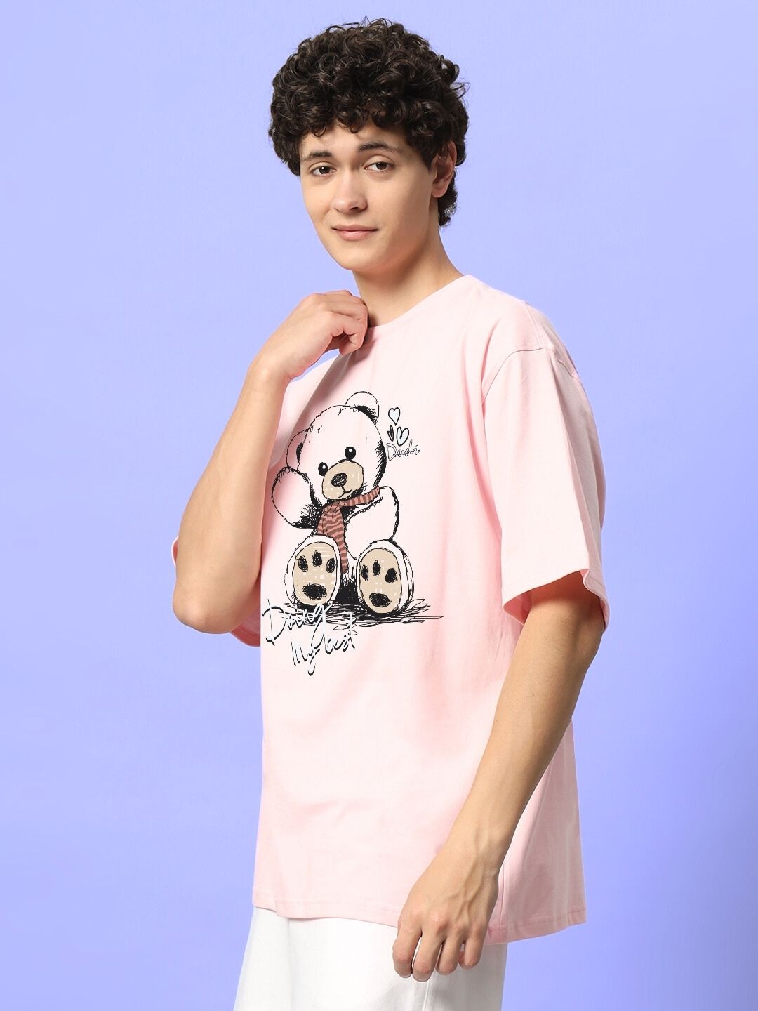 Young person wearing a CUTE BEAR OVERSIZED T-SHIRT PINK with bear graphic, standing against a light lavender background.