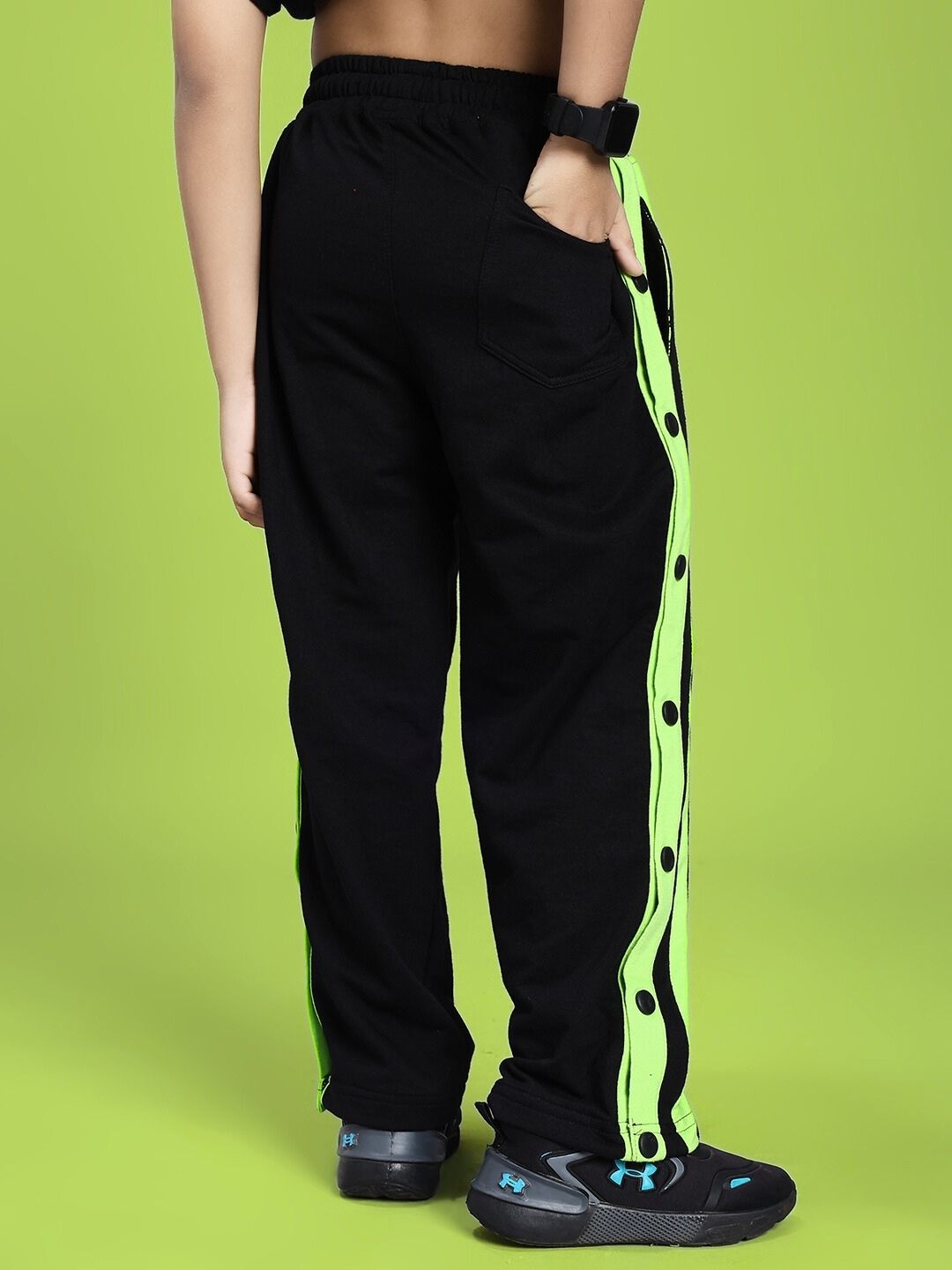 DANCER JOGGER FOR BOYS AND GIRLS BLACK NEON-GREEN with neon-green accents on a model's legs on a green background