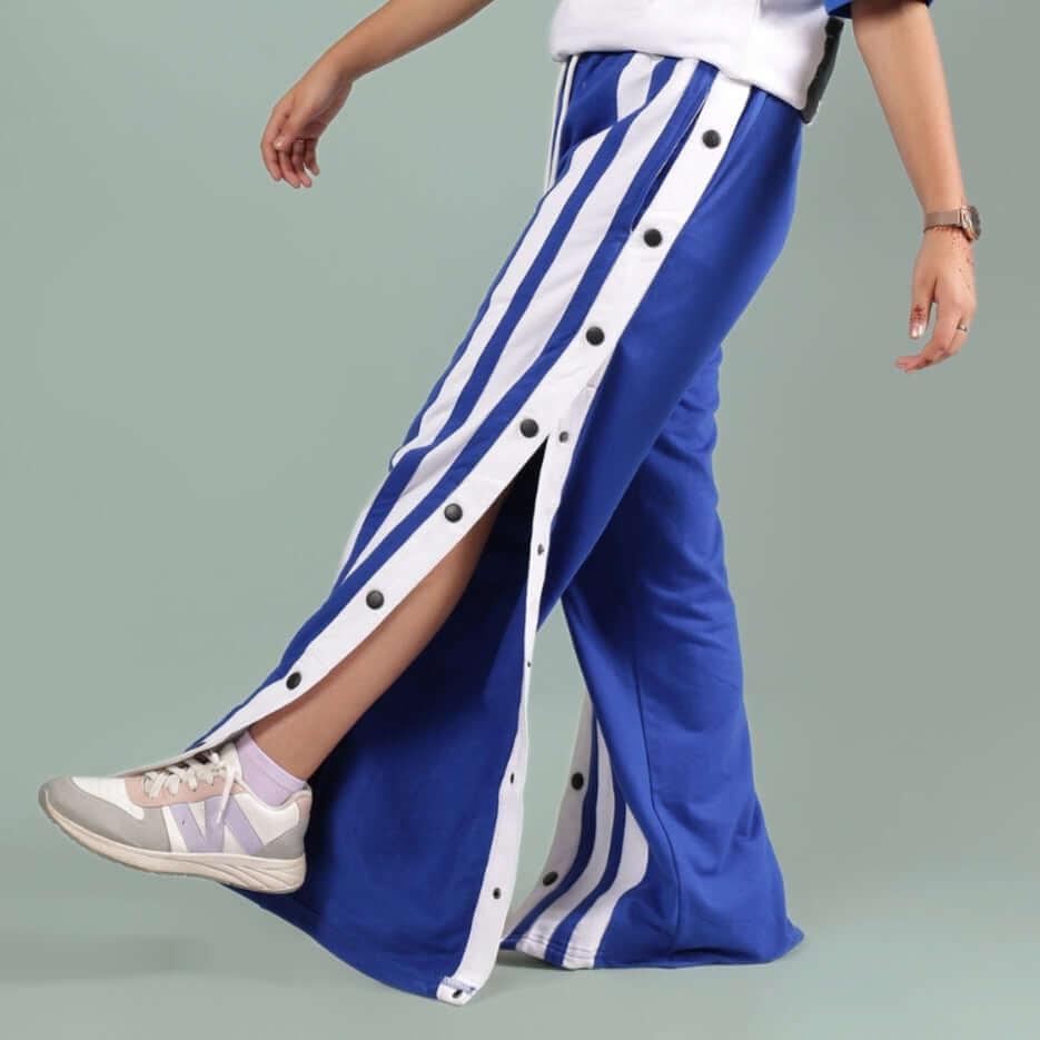 Person wearing DANCER JOGGER FOR BOYS & GIRLS ROYAL BLUE with buttoned side stripes, showcasing flexible athletic style.