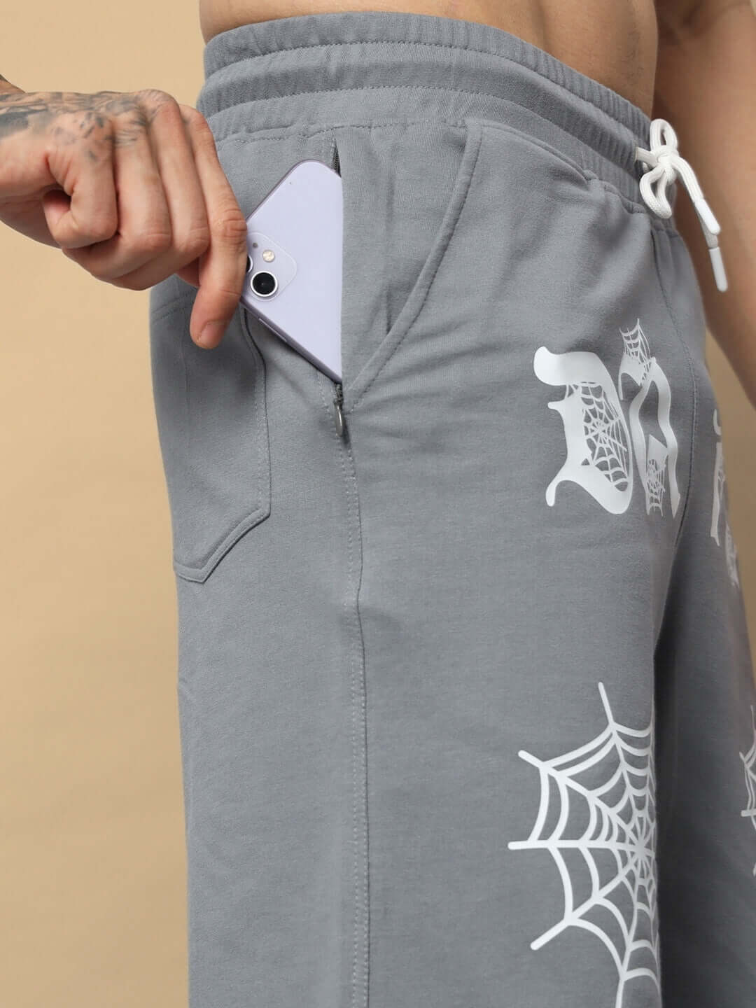 Man wearing grey Dark Web Regular Fit Shorts with phone in pocket, showcasing web design and adjustable waistband.