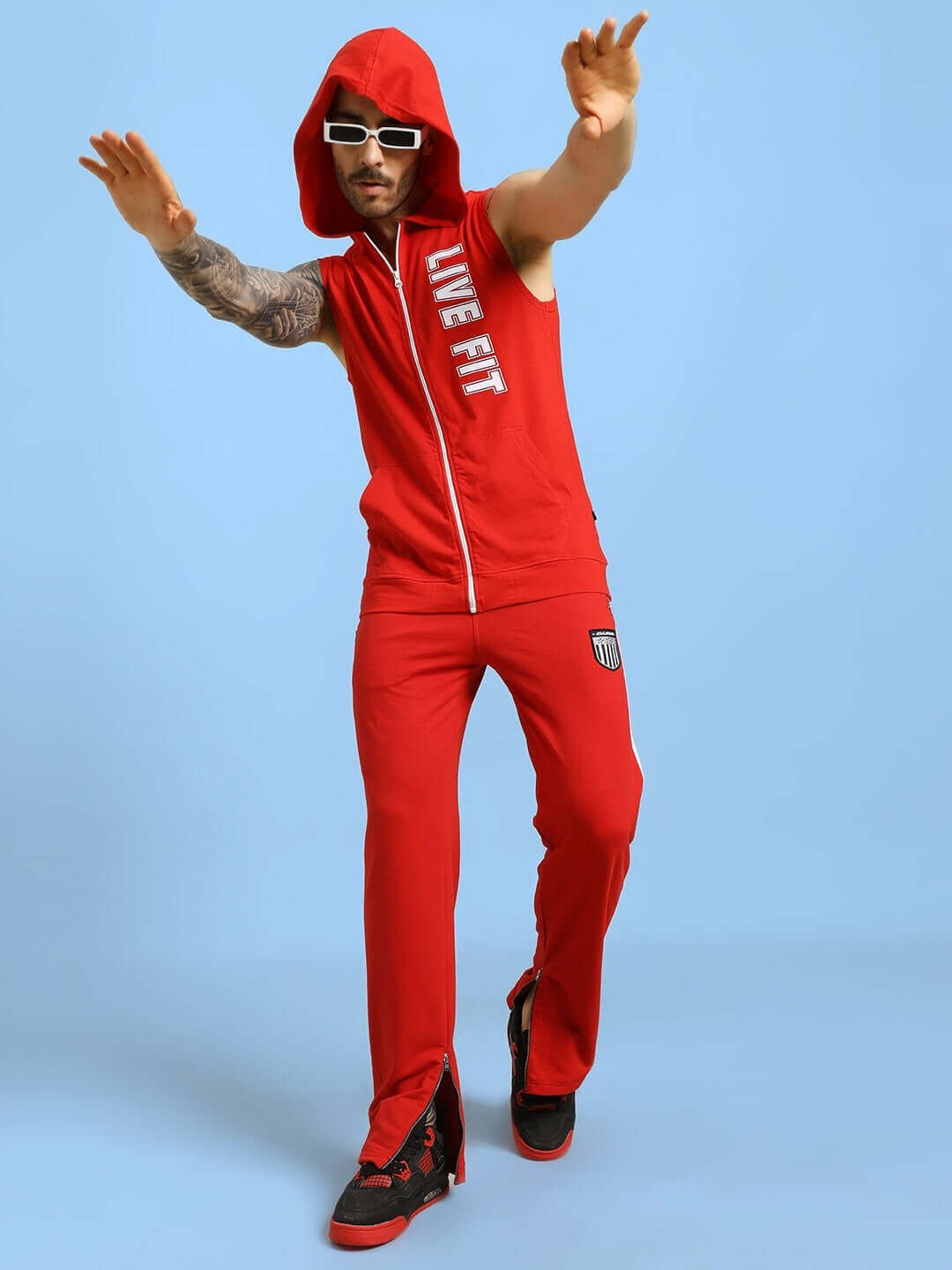 Man wearing Live Fit Gym Hooded T-Shirt in red, performing a dynamic pose, showcasing athletic style and flexibility.
