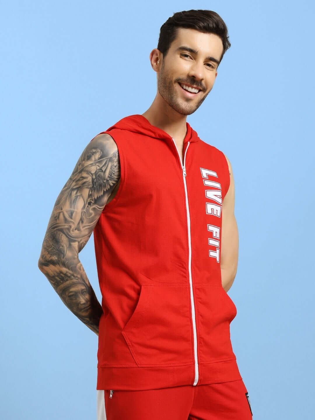 Man wearing a red Live Fit Gym Hooded T-Shirt, flexing in a sleeveless design against a blue background.