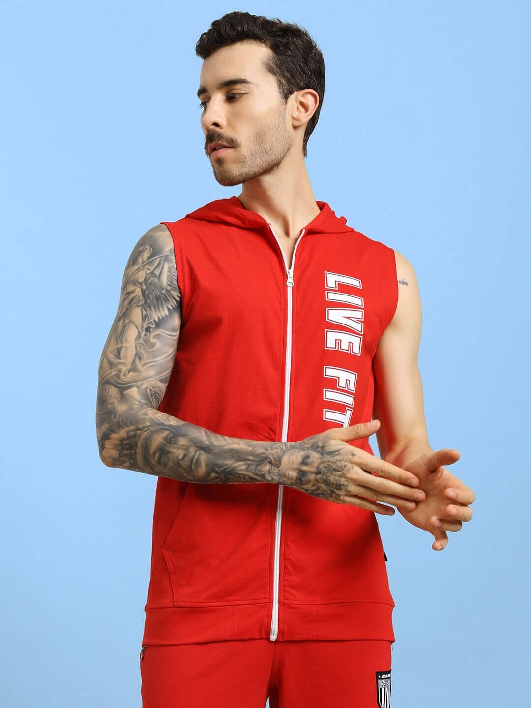 Man wearing a red LIVE FIT gym hooded T-shirt, showcasing breathable and flexible fabric for workouts.