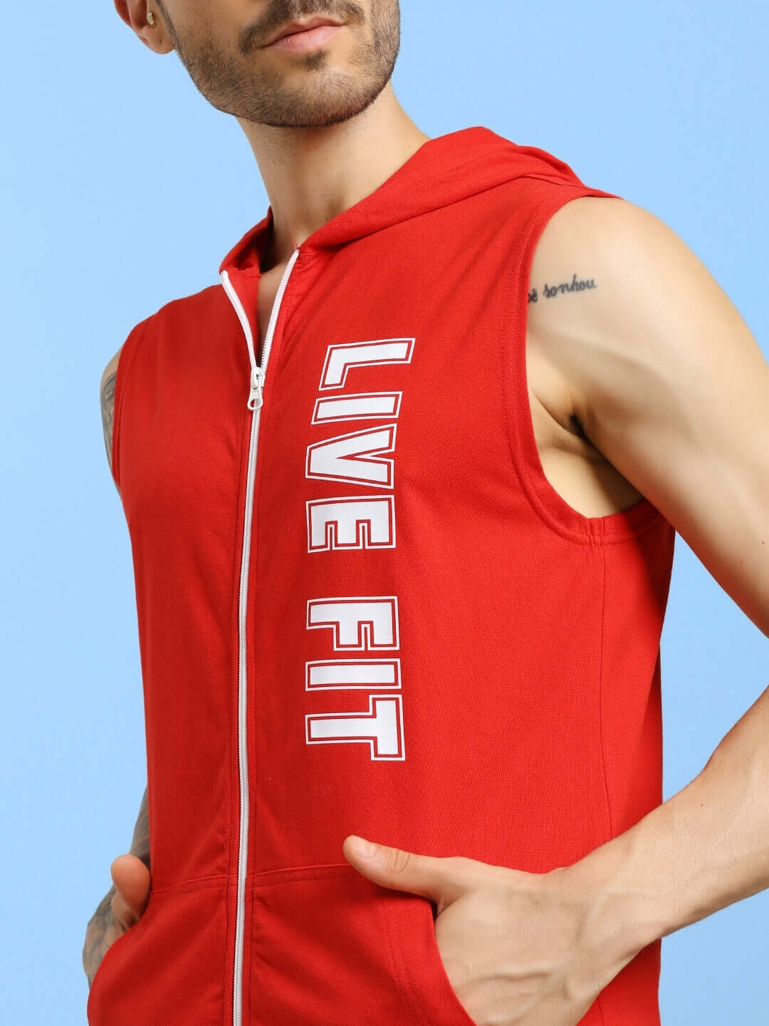 Man wearing a red hooded t-shirt with 'LIVE FIT' text, showcasing gym wear style and flexibility.