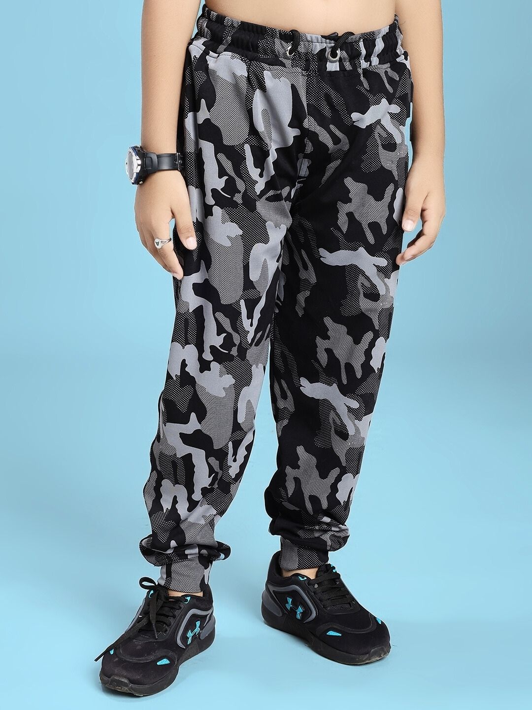 DEFENCE JOGGER FOR BOYS AND GIRLS BLACK GREY with camouflage pattern displayed on child against blue background