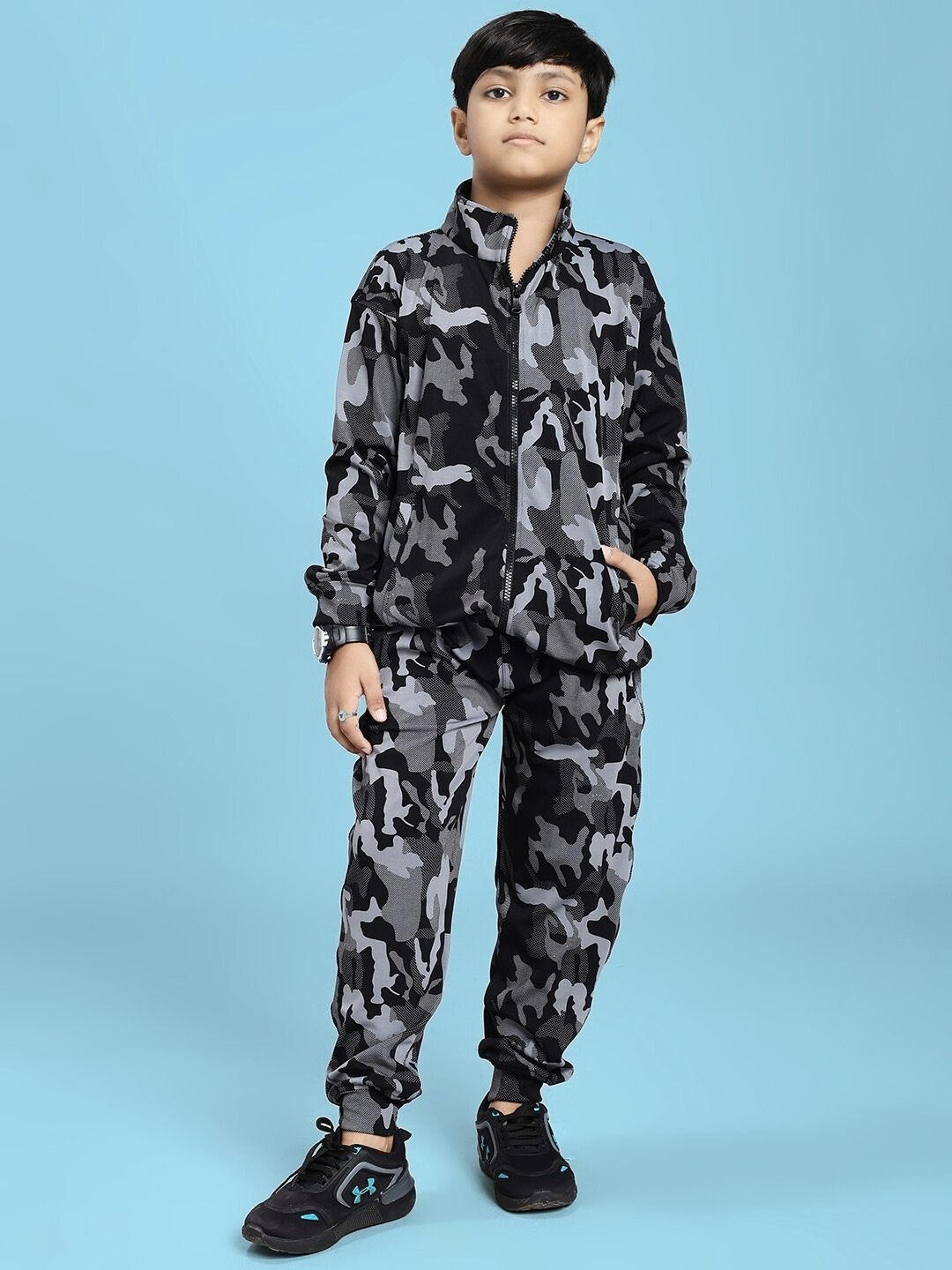 Boy wearing DEFENCE JOGGER FOR BOYS AND GIRLS BLACK GREY with black sneakers on a blue background