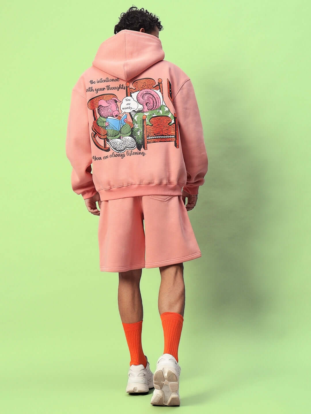 Rear view of a model wearing DELIBERATE FLEECE CO-ORD PEACH, featuring a stylish fleece hoodie and shorts lounge set in peach.