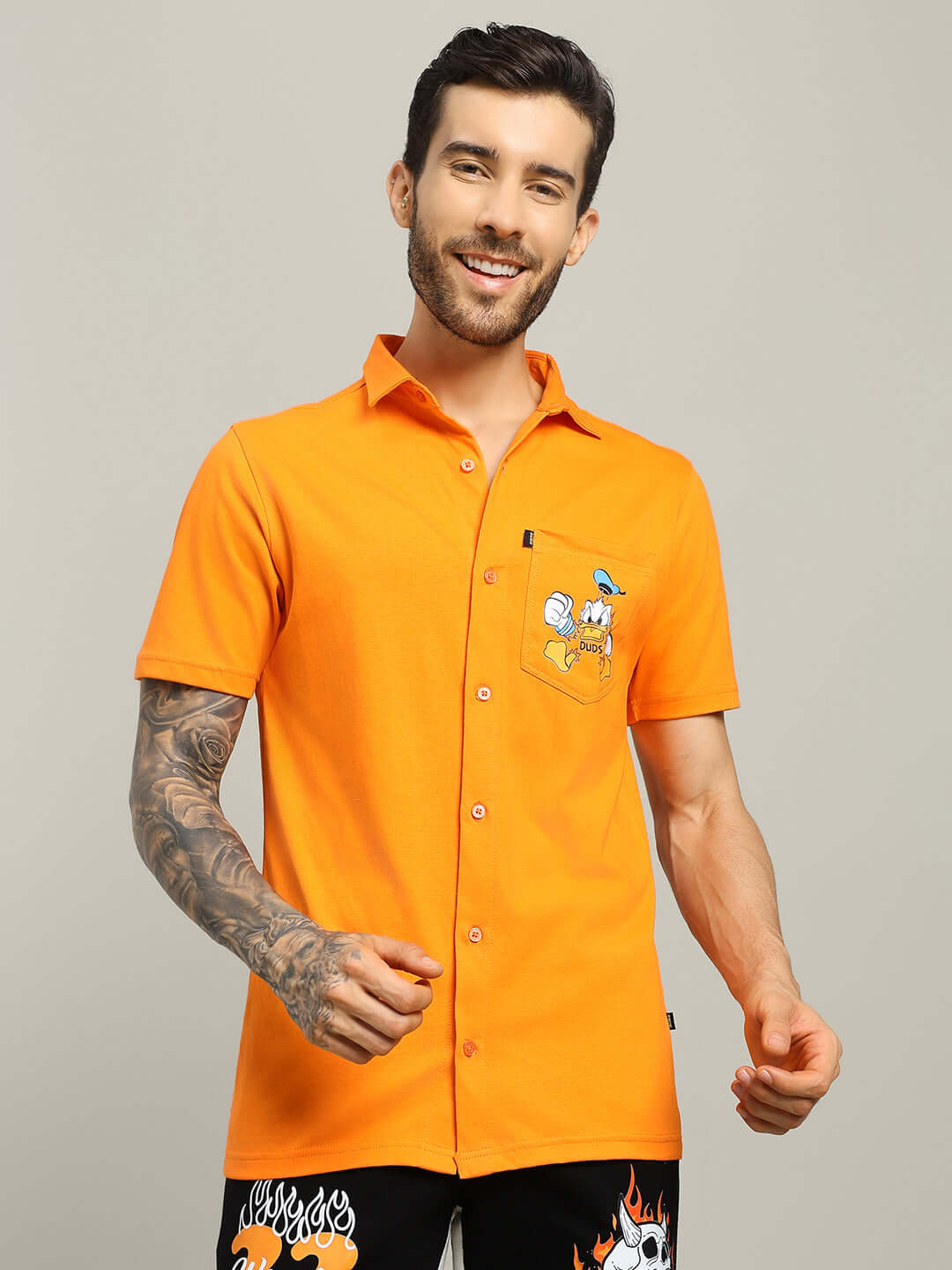 Man wearing DELLA Regular Fit Shirt in orange, featuring cartoon embroidery. Tailored by DUDS with customizable size option available.
