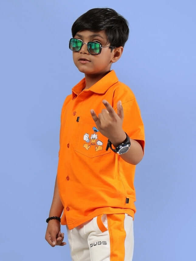 Boy wearing DELLA SHIRT FOR BOYS & GIRLS ORANGE, showcasing playful design and vibrant color, ideal for casual outfits and outdoor fun.