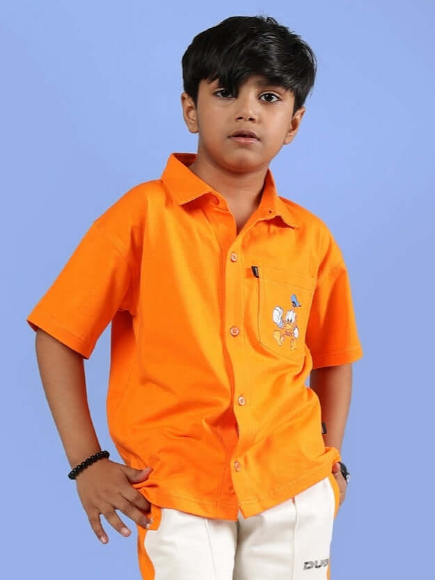 Child wearing DELLA orange shirt from DUDS, unisex design for boys and girls, with custom fit option available.