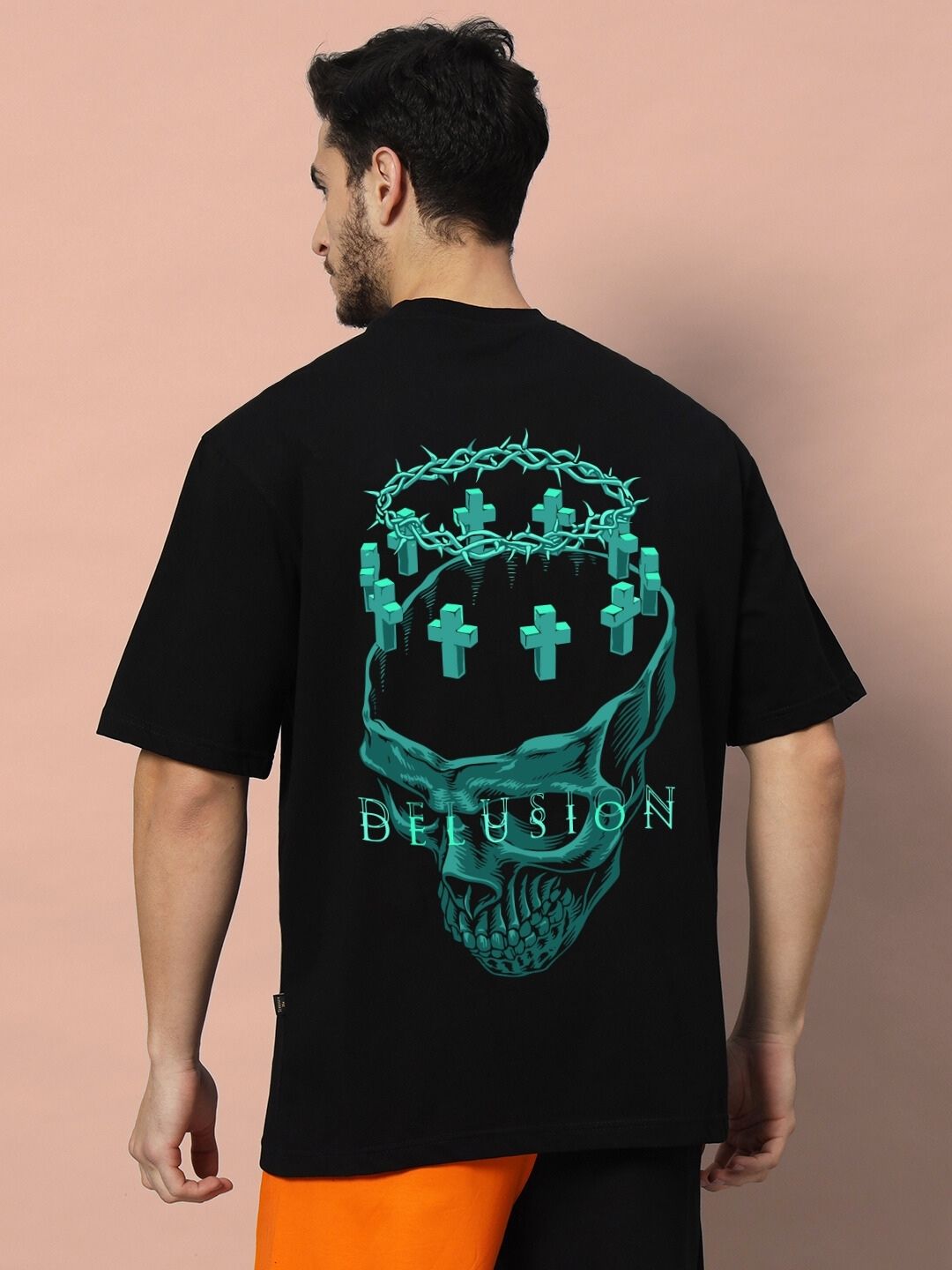 Man wearing DELUSION OVER-SIZED T-SHIRT BLACK with green skull and barbed wire design on the back.