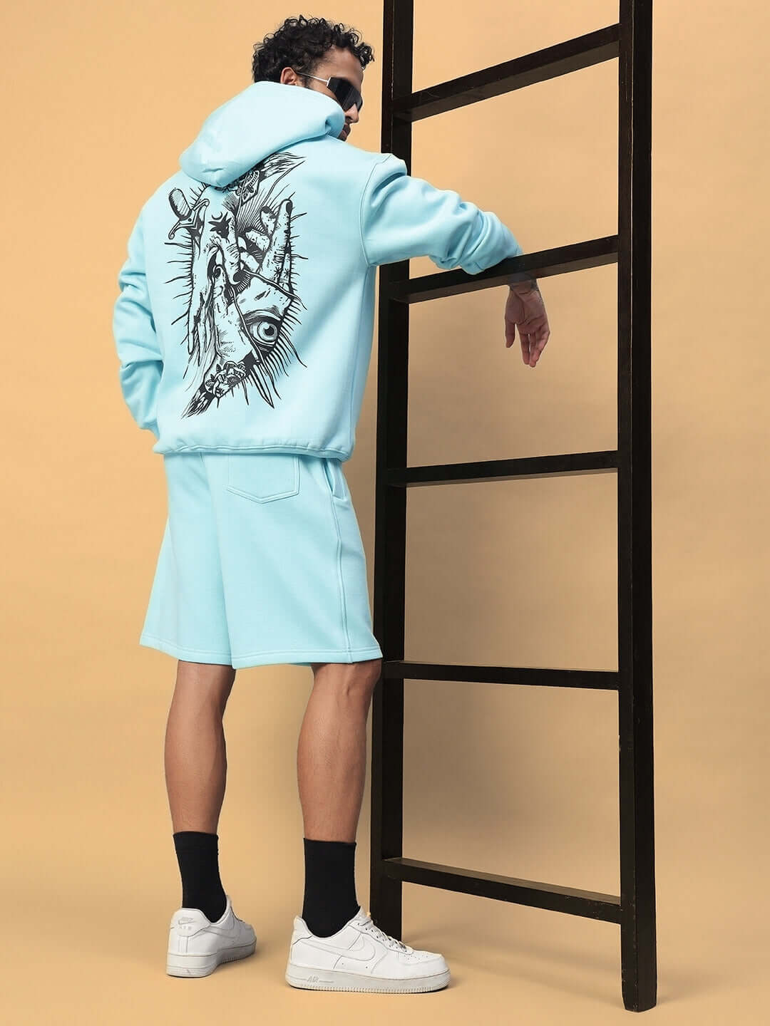 Man wearing WEARDUDS DEMON FLEECE HOODIE SKY BLUE, standing by a ladder.