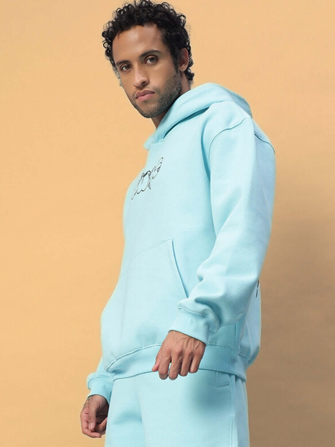Man wearing WEARDUDS DEMON FLEECE HOODIE SKY BLUE with hands in pockets, showcasing custom fit option and premium tailoring.
