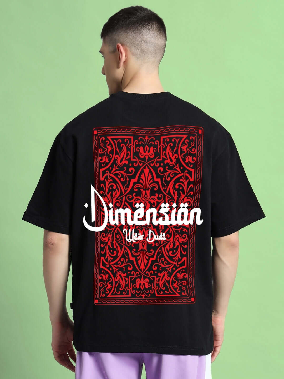 Model wearing Dimension over-sized T-shirt in black with intricate red design, made of premium cotton French terry.