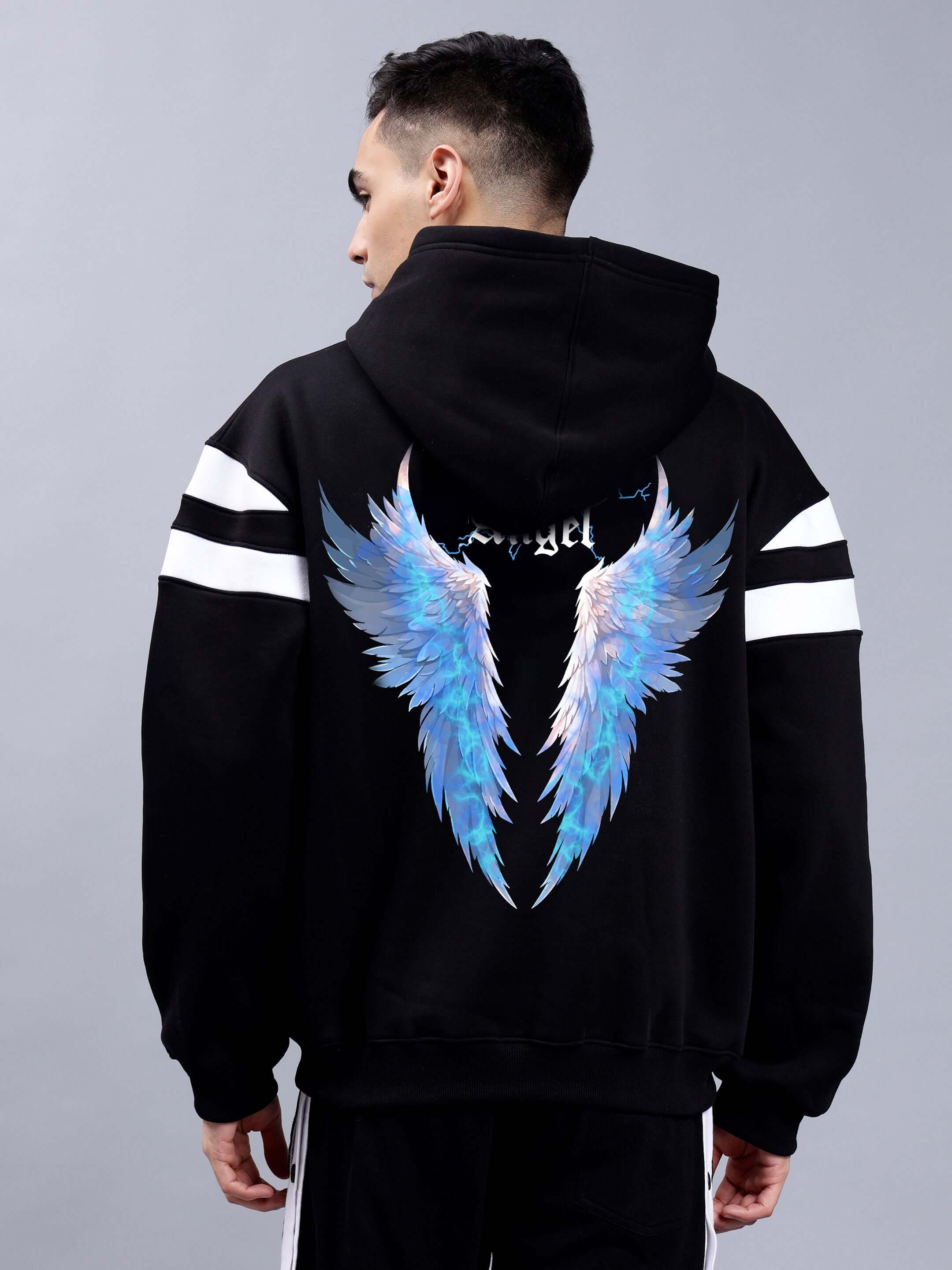 Back view of a black colorblock oversize hoodie featuring divine spirit blue wing design, worn by a person. Fashion streetwear style.