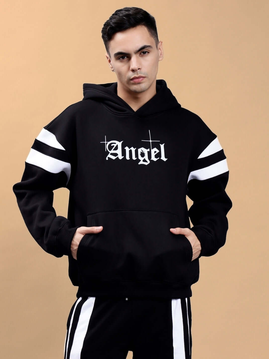 Model wearing a black 'Divine Spirit' colorblock oversized hoodie with 'Angel' text and white stripe details on a beige background.