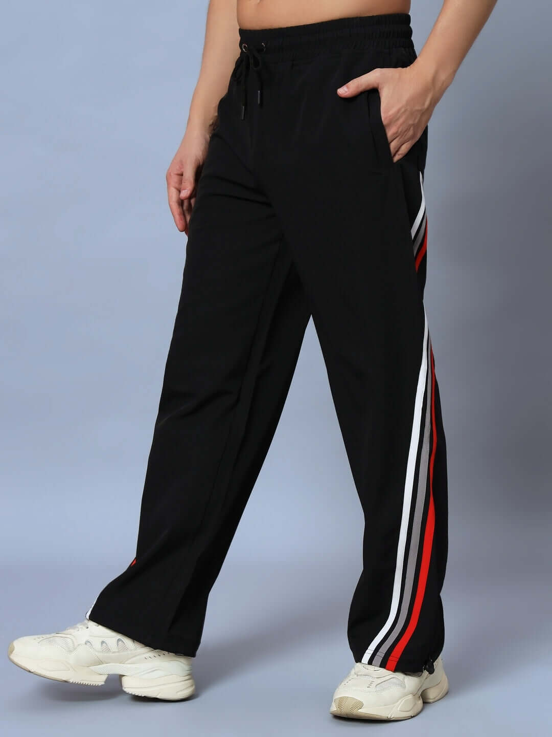 Black relaxed fit jogger with side stripe detail and drawstring waist, showcased by a model wearing white sneakers.