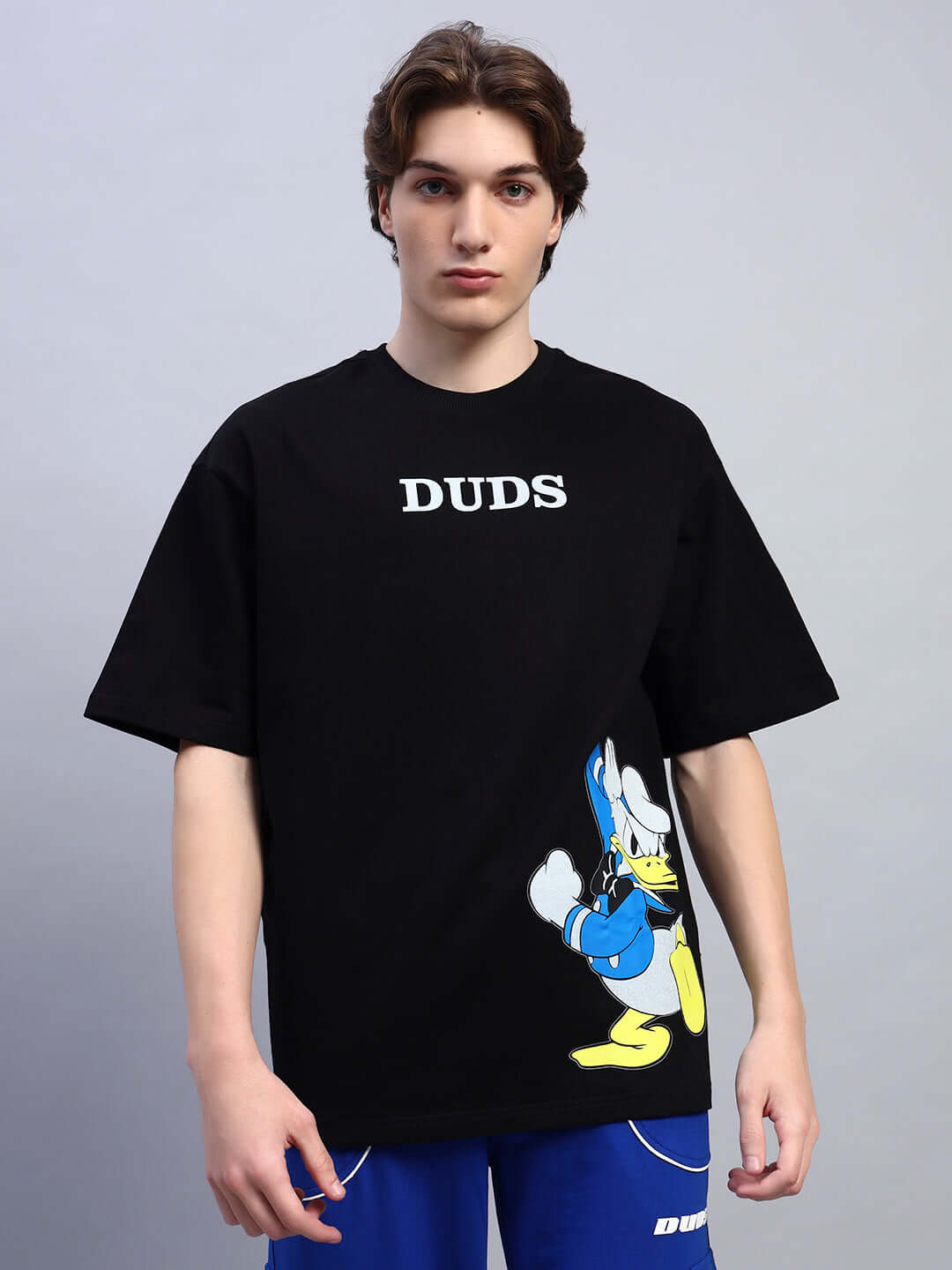 Black oversized t-shirt with Donald Duck print, premium cotton, worn by a male model, features bold 'DUDS' text.