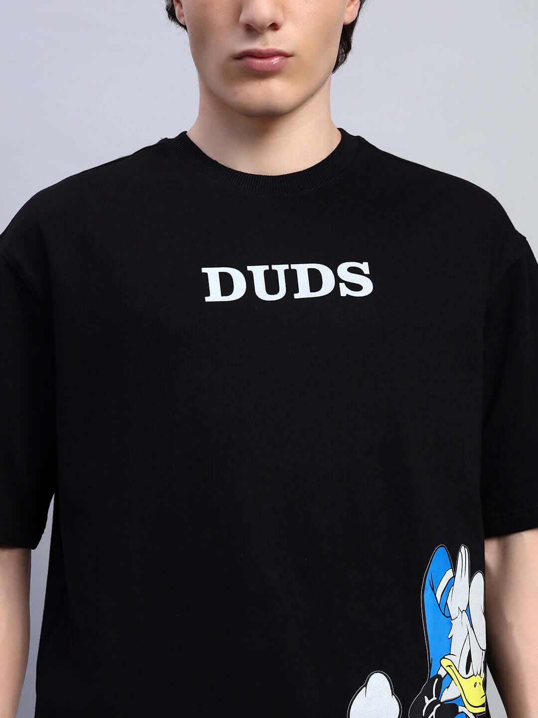 Man wearing DONALD DUCK PRINTED OVERSIZED T-SHIRT BLACK with bold graphic