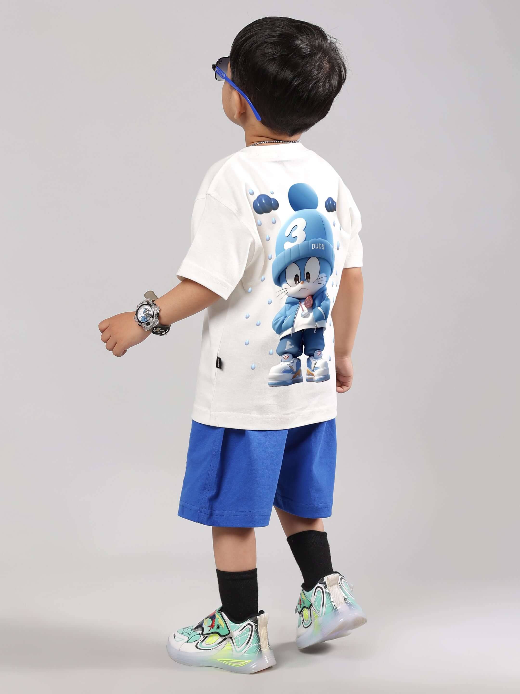 Child wearing DORAEMON Summer Co-ord in off white and royal blue, featuring a graphic t-shirt and shorts, suitable for boys and girls.