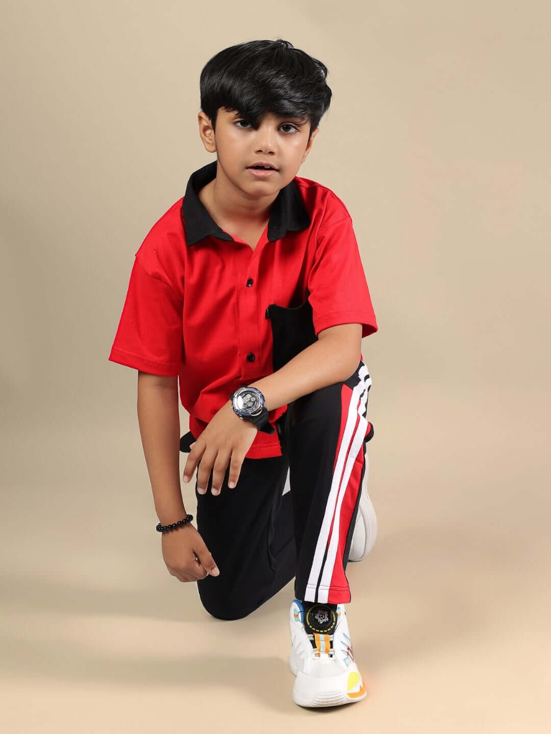 Child wearing a red-black Doric co-ord set featuring a collared shirt and striped pants, customizable for boys and girls by DUDS.