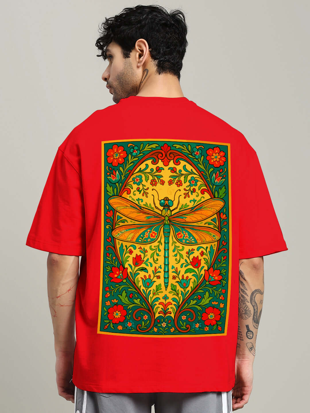 Red oversized t-shirt with vibrant dragonfly design on back, crafted from premium heavy gauge fabric. Features colorful floral motifs.