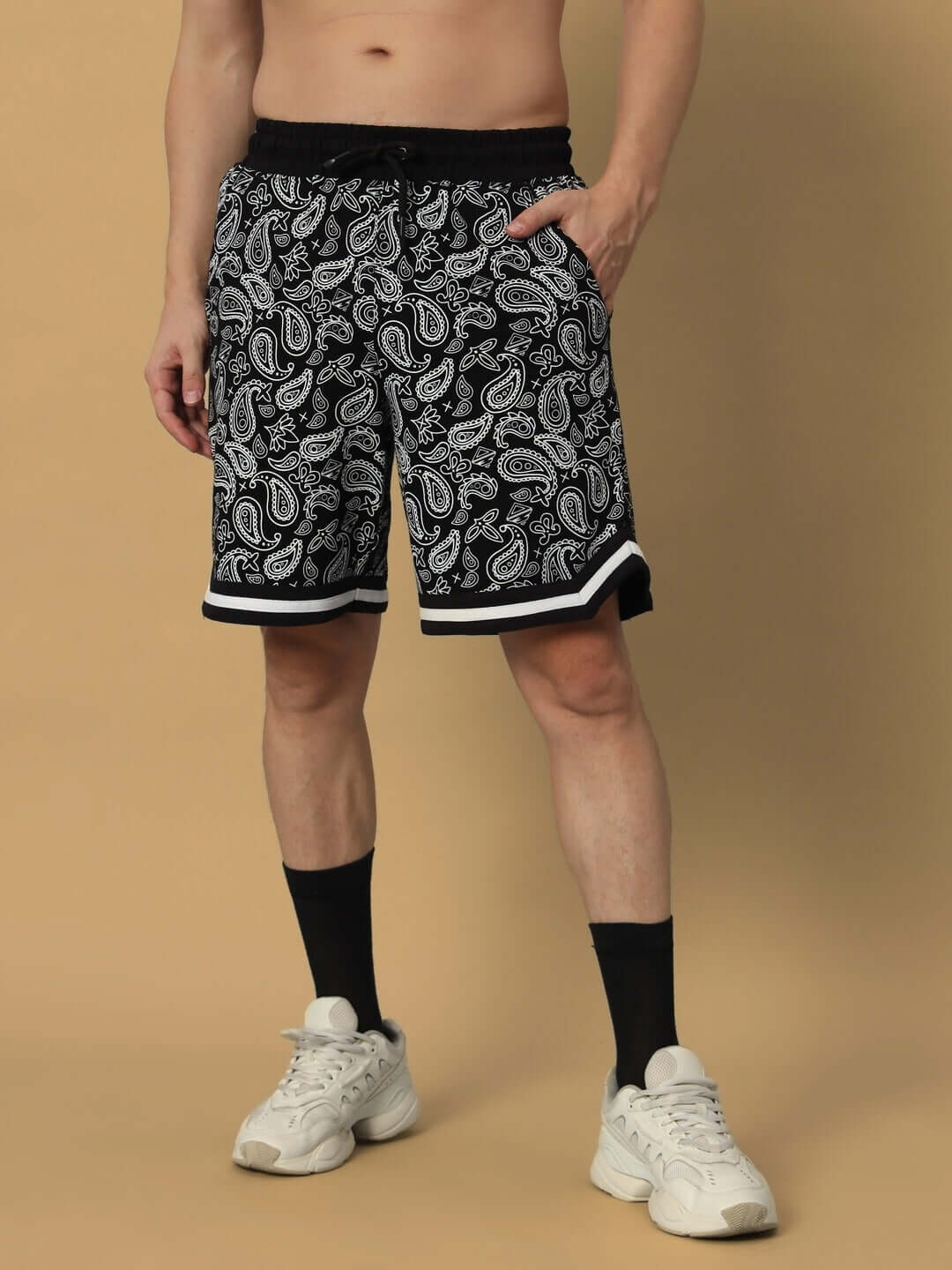 Man wearing Drizzle Regular Fit Shorts in black with paisley pattern, featuring a comfortable elastic waistband and stylish design.