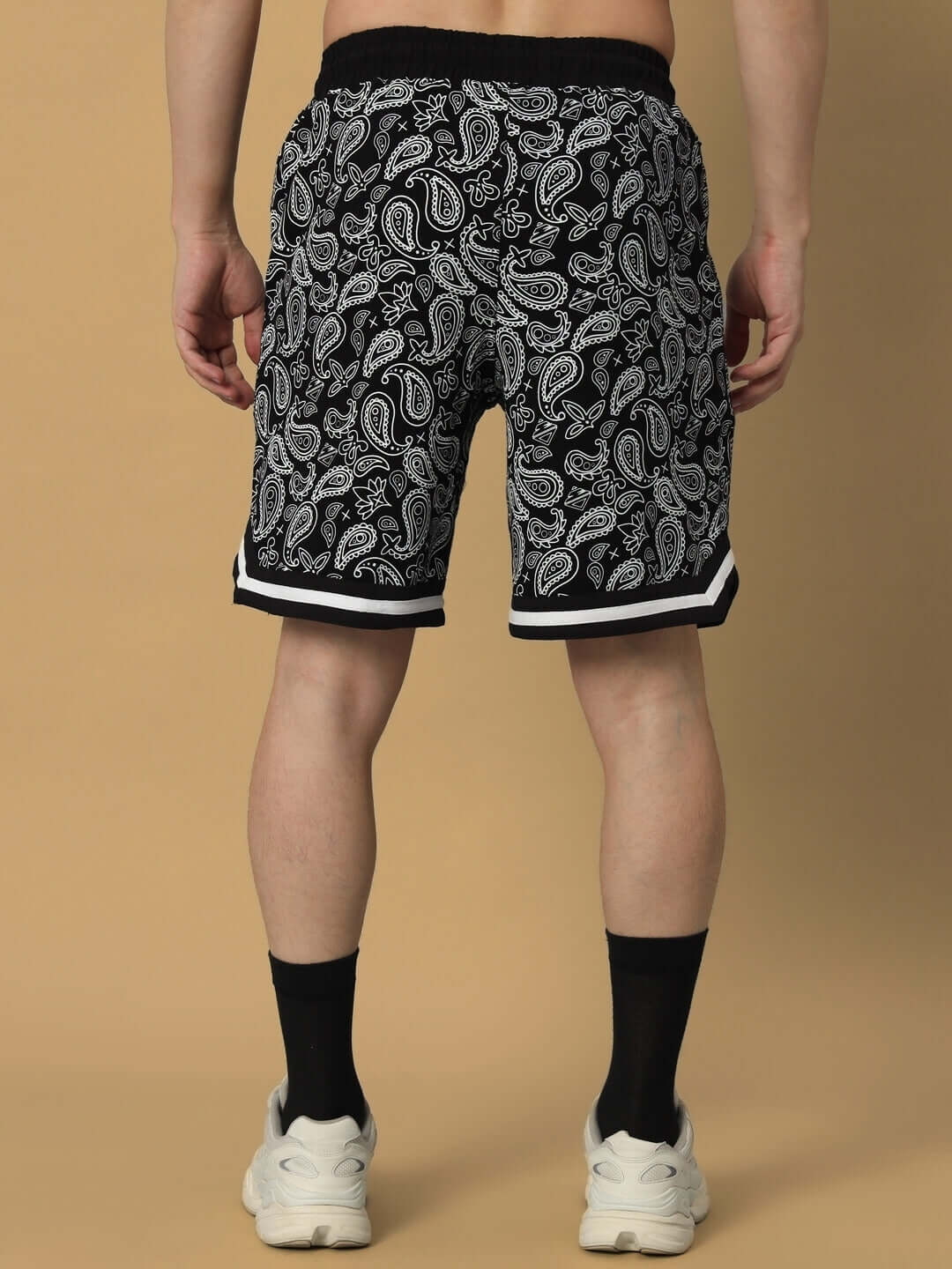 Rear view of a person wearing Drizzle Regular Fit Black Shorts with paisley patterns, showcasing detailed design and sporty style.