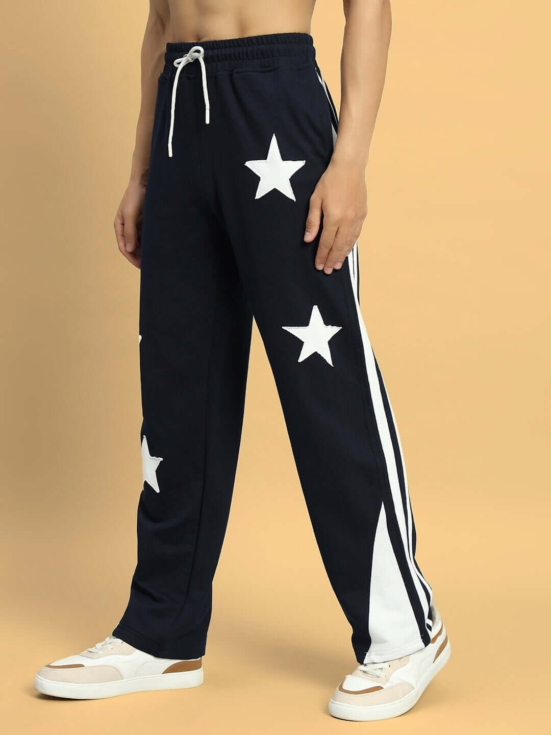 Male model wearing navy blue joggers with star design, showcasing relaxed fit and white side stripe detail.