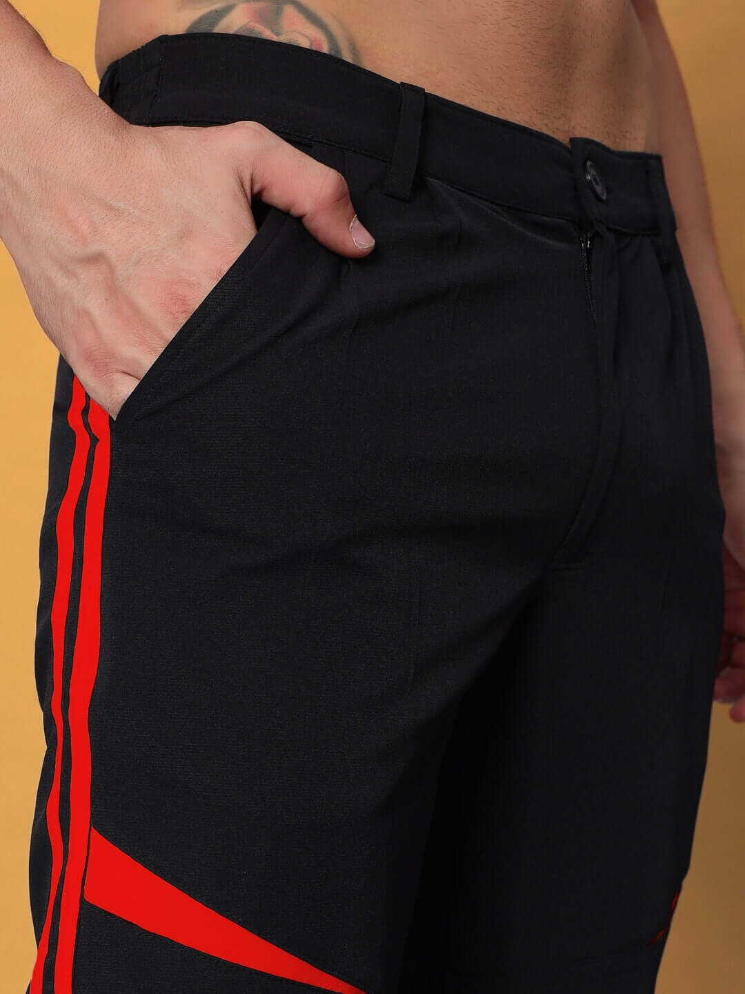 Close-up of DROVE RELAXED FIT CARGO PANTS BLACK RED, featuring side pockets and bold red stripes.