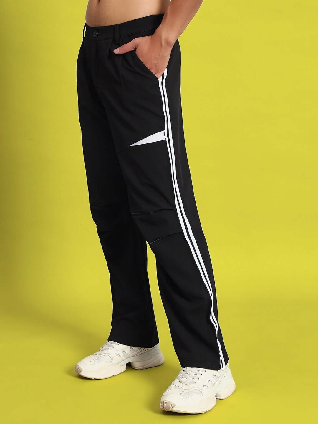DROVE relaxed fit black cargo pants with side pockets and white stripe detail, modeled on a yellow background.