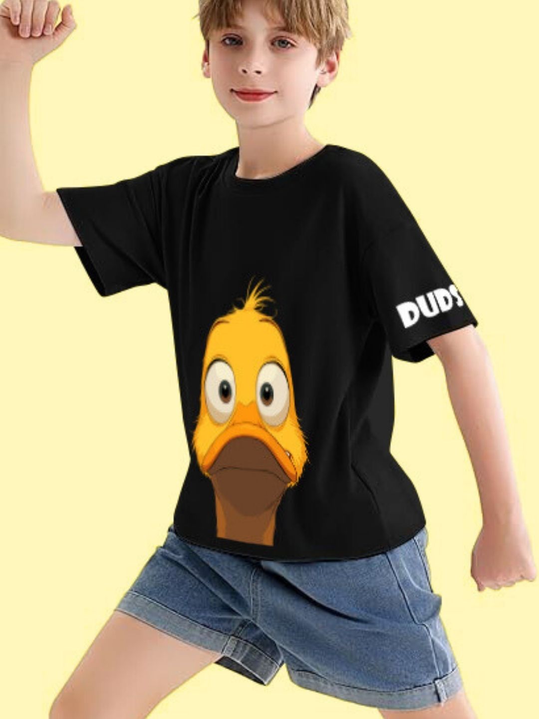 Child wearing DUCK FACE T-SHIRT FOR BOYS AND GIRLS BLACK with duck graphic, standing confidently in shorts.