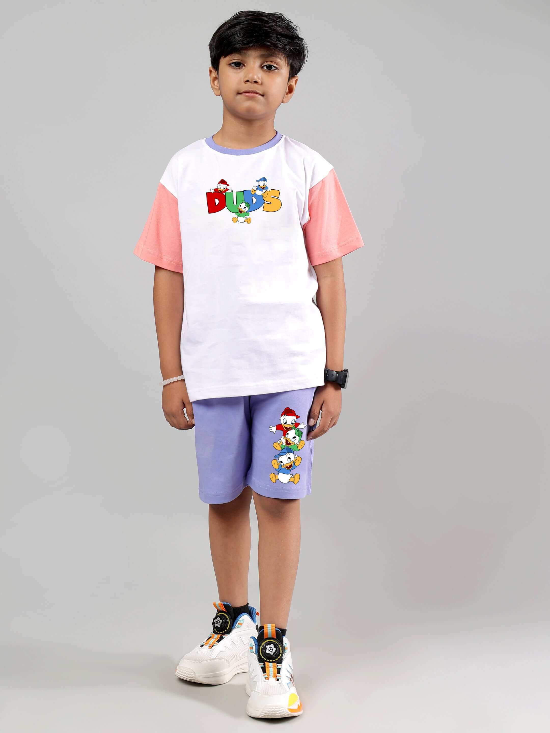Boy wearing white lavender Duck Play Co-ord from DUDS, featuring white t-shirt and lavender shorts with playful duck design.