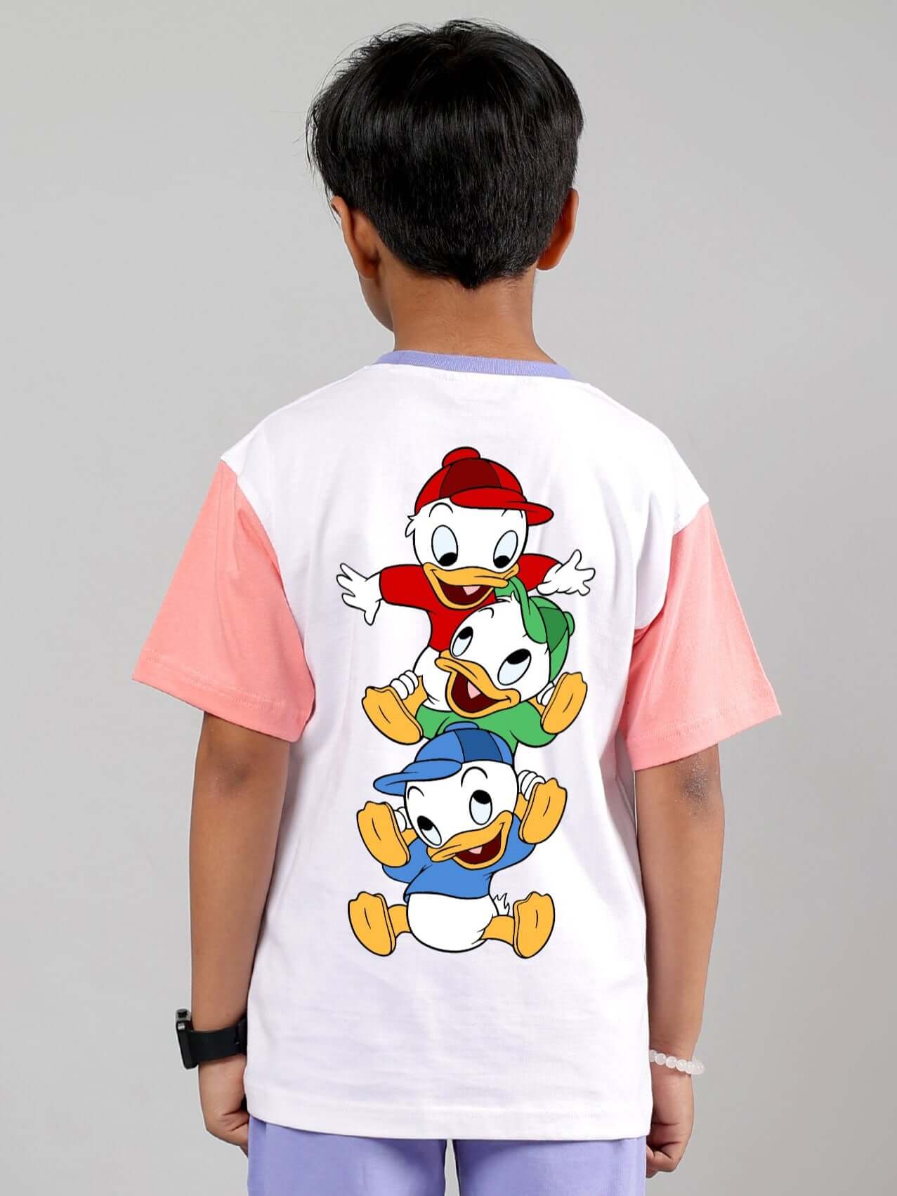 Child wearing a white-pink Duck Play T-shirt with cartoon characters on the back, suitable for boys and girls.