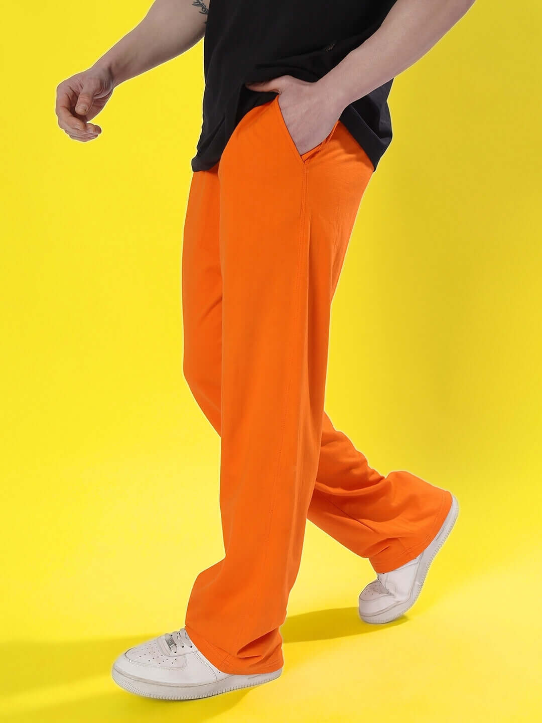 Person wearing DUDS Limited Edition Orange Jogger with white sneakers against a yellow background.