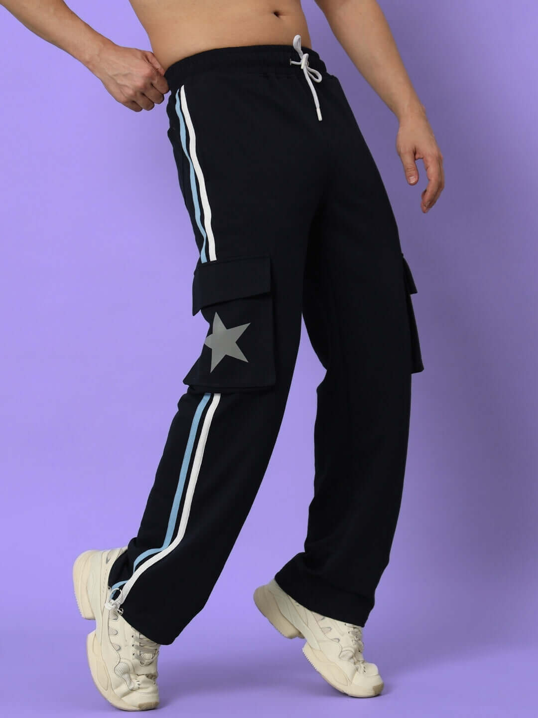 Model wearing navy blue DUDS FORCE joggers with side stripes, cargo pockets, and star detail, standing against a purple background.