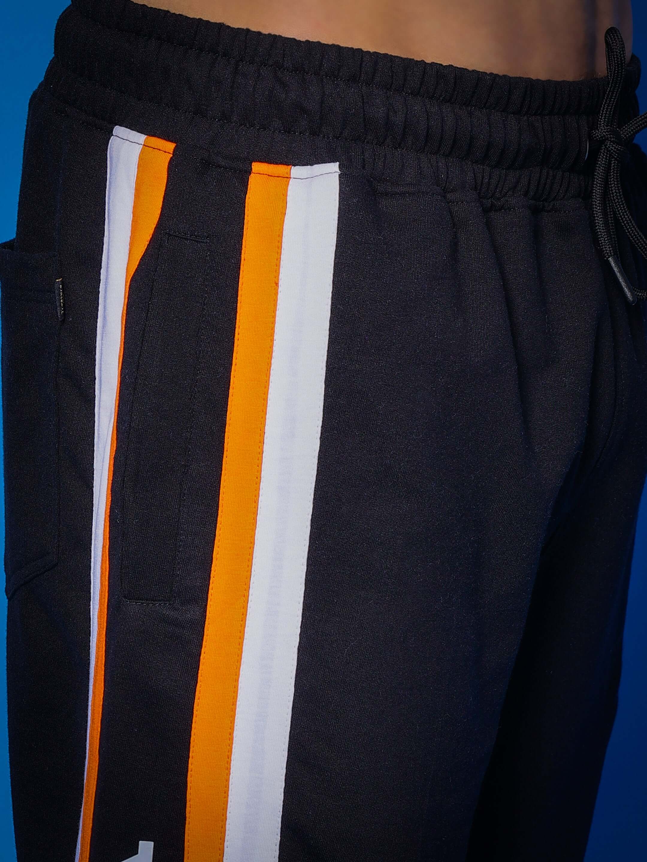 Close-up of black joggers with orange and white stripe detail from DUDS, showcasing quality tailoring and custom fit option.