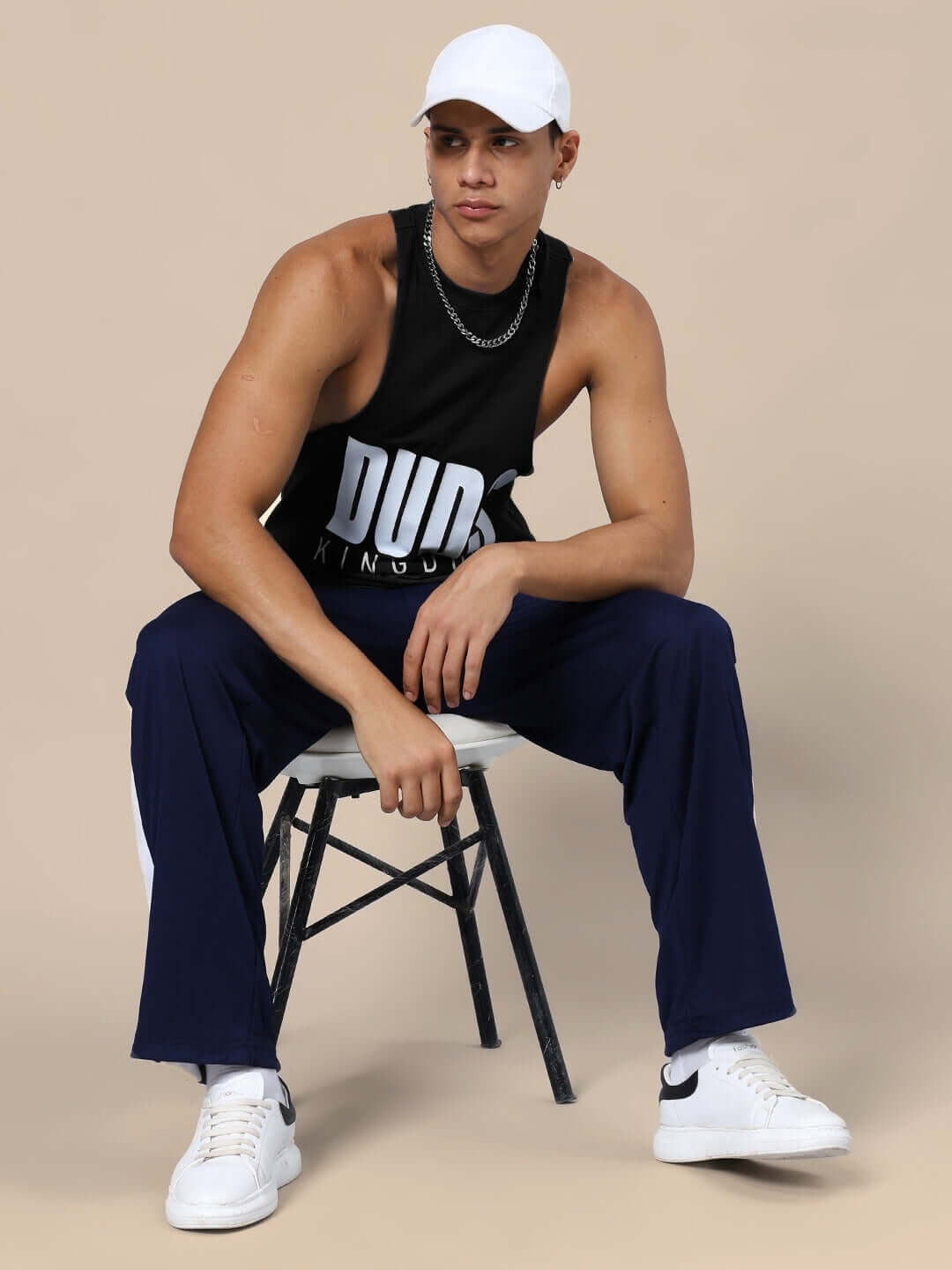 Model wearing DUDS KINGDOM GYM CO-ORD SET BLACK NAVY-BLUE with relaxed fit joggers and tank top, seated on a chair.