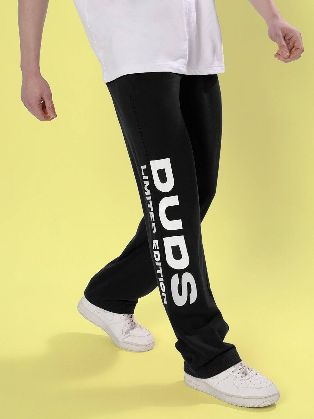 Man wearing DUDS Limited Edition Black Jogger with white sneakers on yellow background, highlighting custom fit option and tailored craftsmanship.