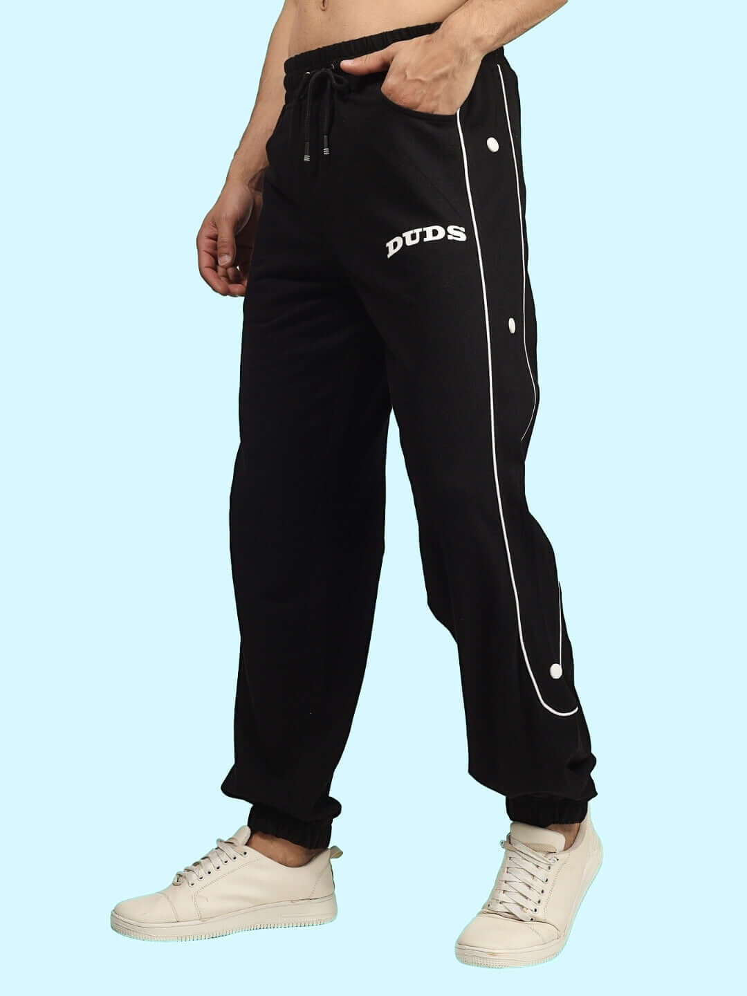 DUDS Moon Night Joggers in black, made-to-order with customizable fit, worn by a model standing in white sneakers on a light blue background.