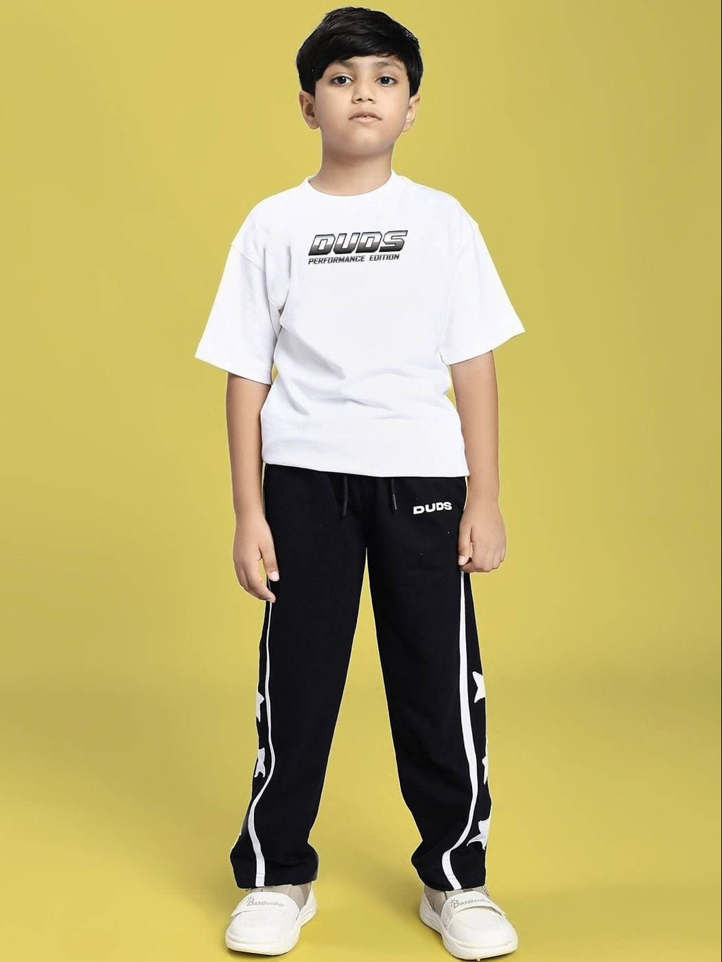 Boy wearing DUDS PERFORMANCE T-SHIRT FOR BOYS AND GIRLS WHITE standing in front of yellow background.