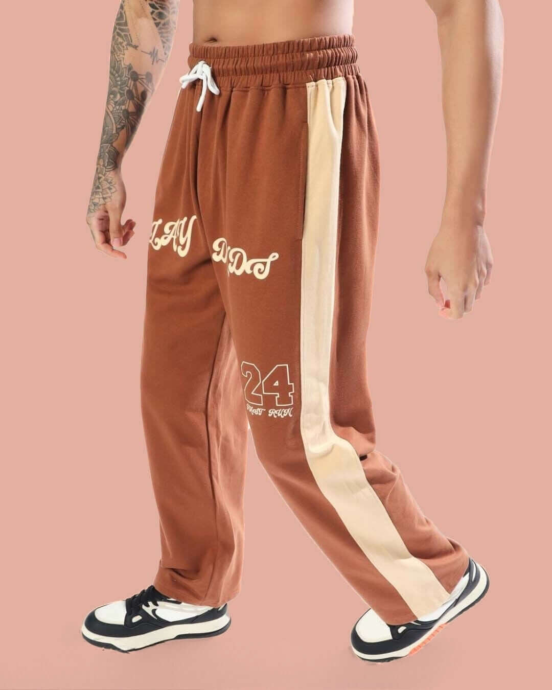 Model wearing DUDS PLAY Baggy Joggers in brown-beige with side stripe, showcasing comfort and style.