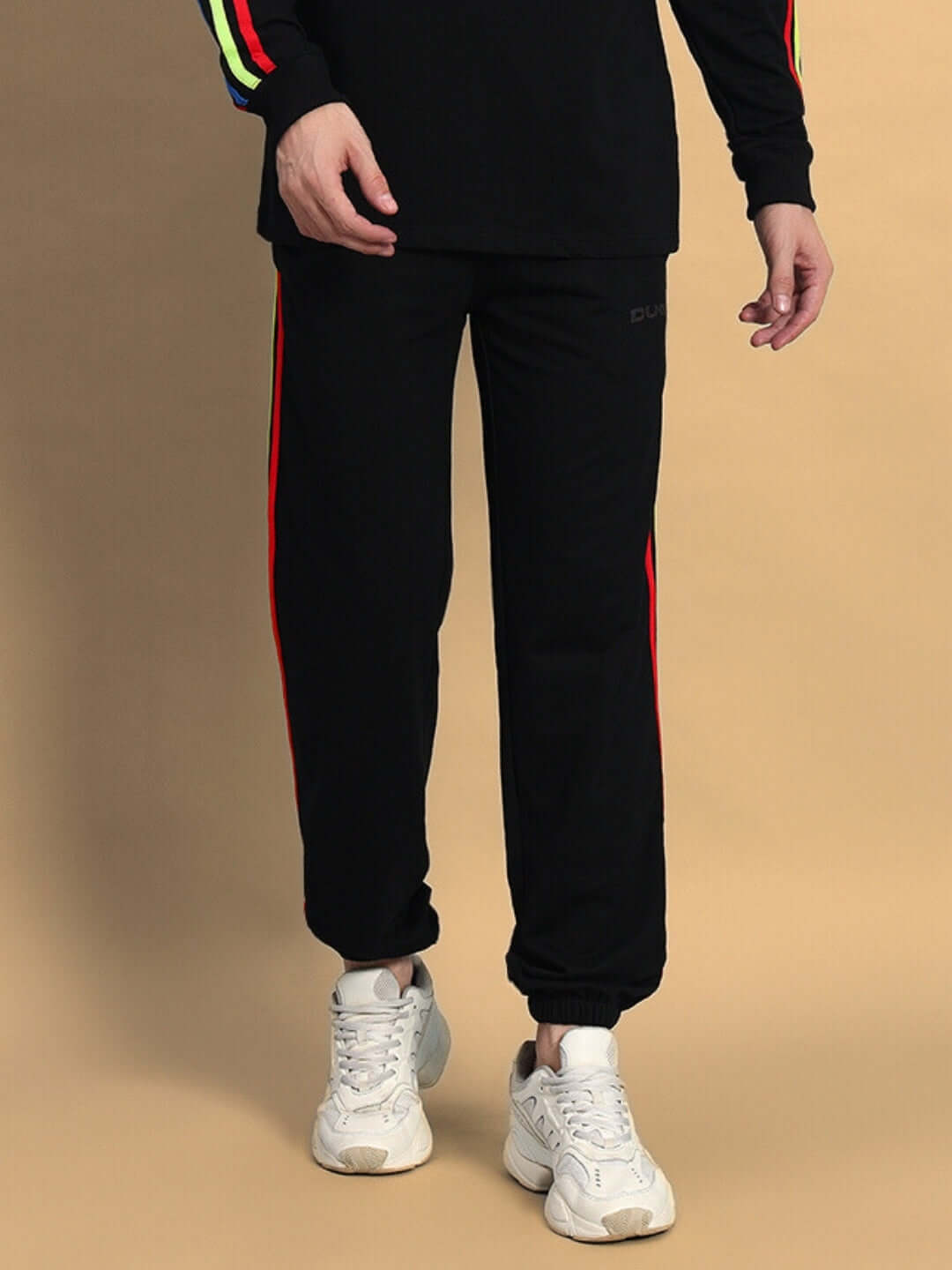 Man wearing DUDS Rainbow Colorful Stripe Joggers in black, featuring vibrant side stripes, paired with white sneakers.