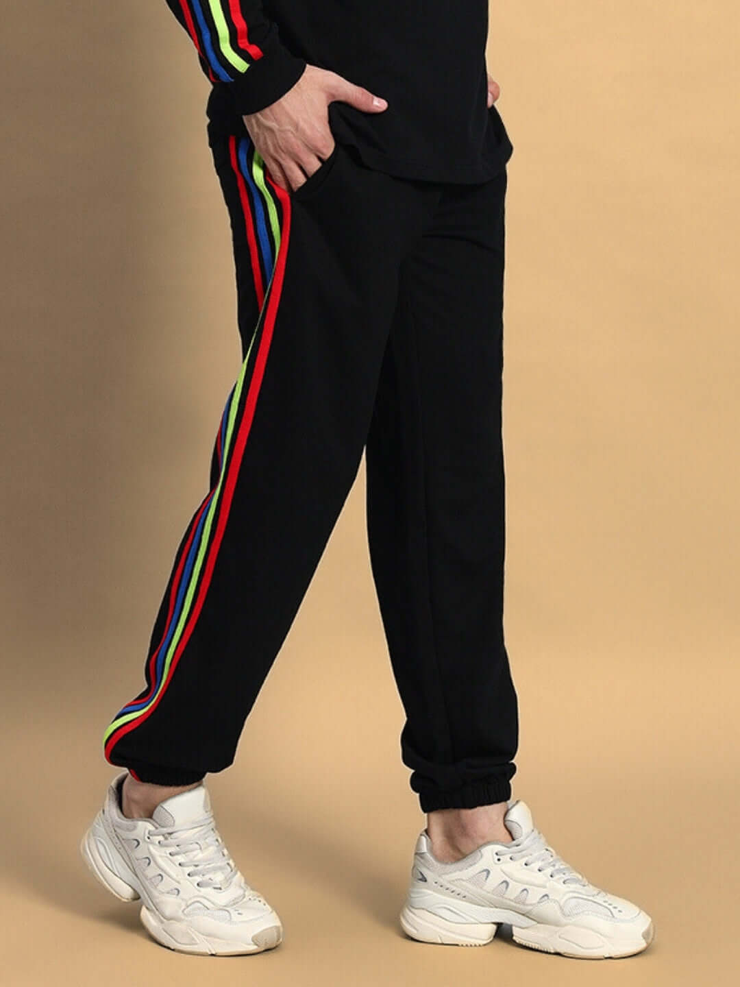 Men's black joggers with rainbow stripes by DUDS, made to order, showing left side profile, paired with white sneakers.