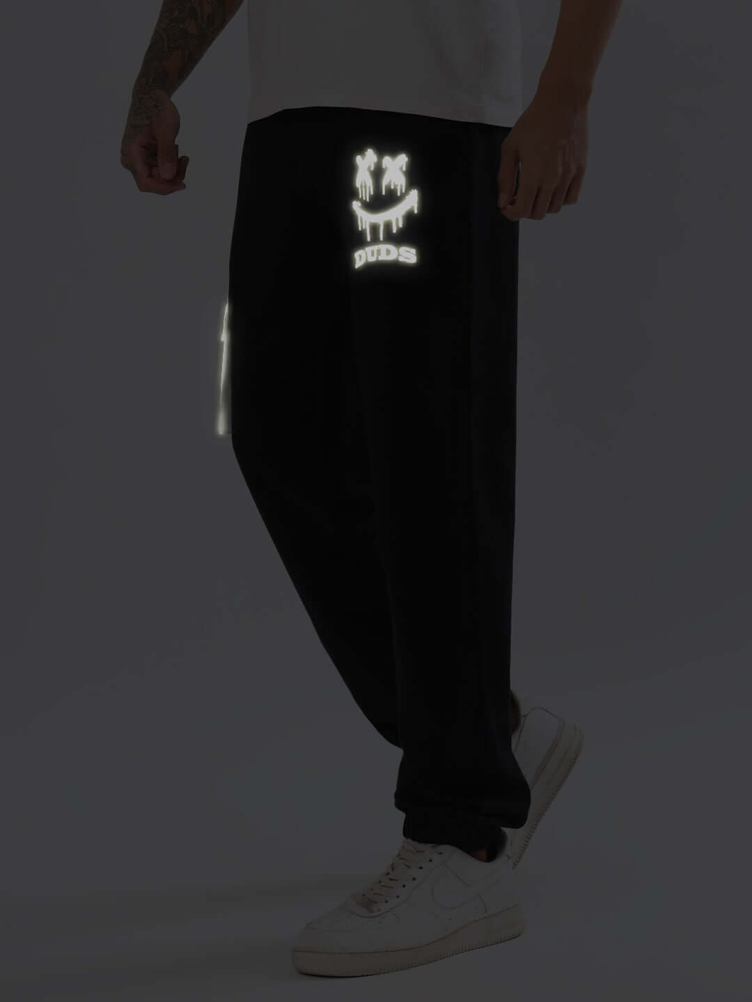 DUDS Smiley Reflector Cargo Jogger in Black with reflective details, customizable fit option available, worn with white sneakers.