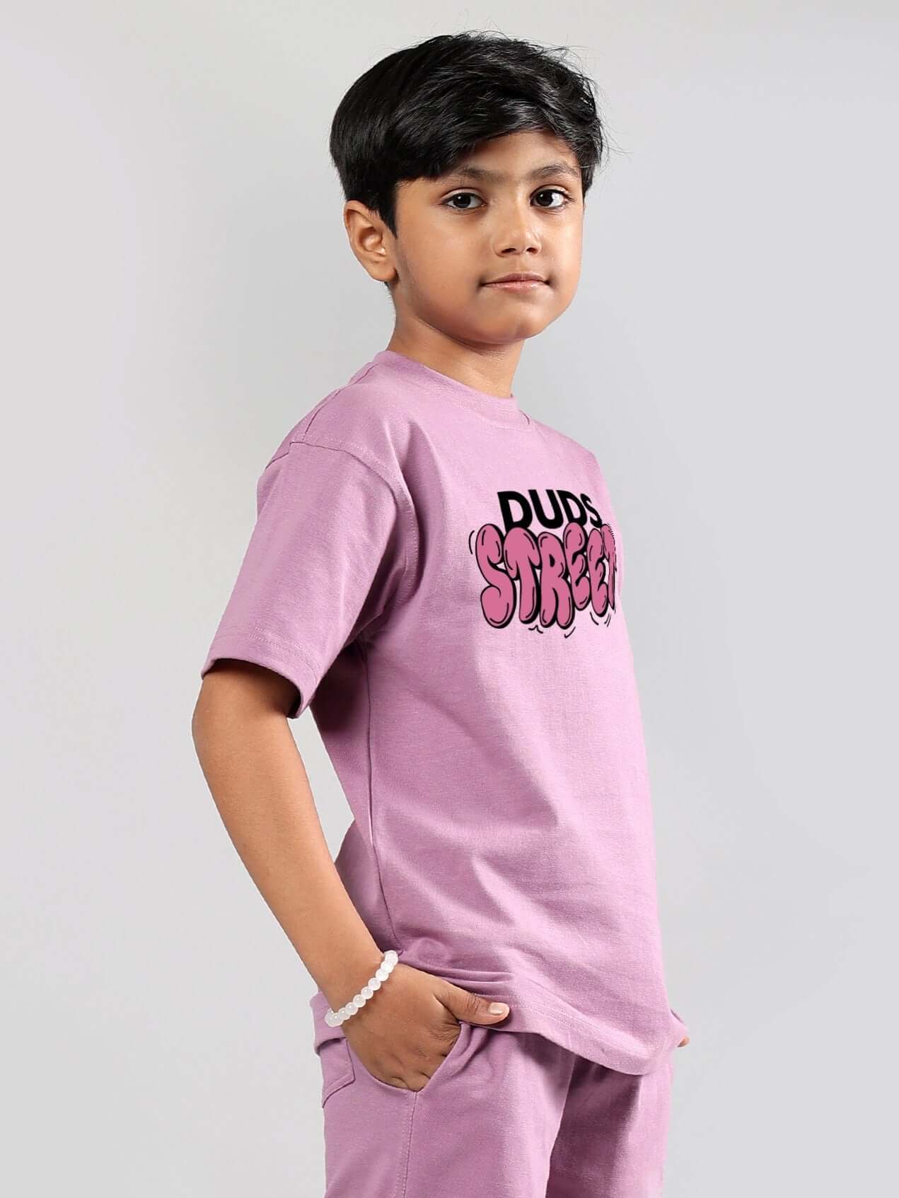 Young boy wearing DUDS STREET printed t-shirt in plum purple, designed for boys and girls, showcasing a casual and trendy look.