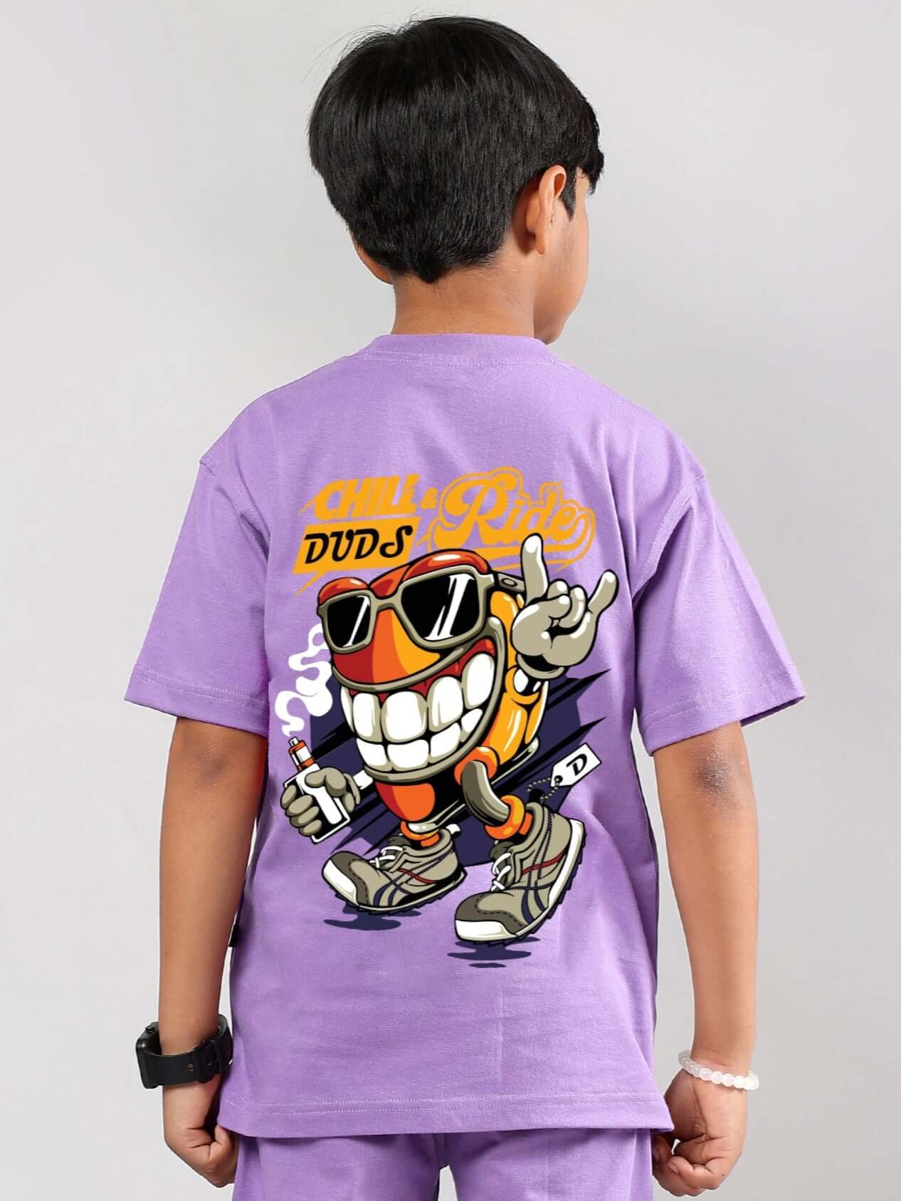 Boy wearing lavender DUDS Chill & Ride t-shirt with playful cartoon design, suitable for boys and girls.