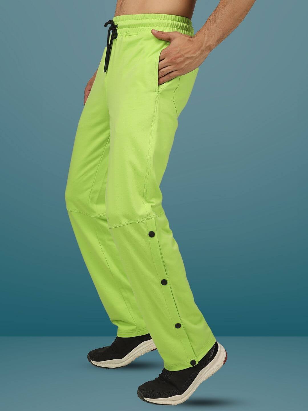 Side view of a person wearing neon green racer joggers with button details from DUDS, styled with black sneakers.