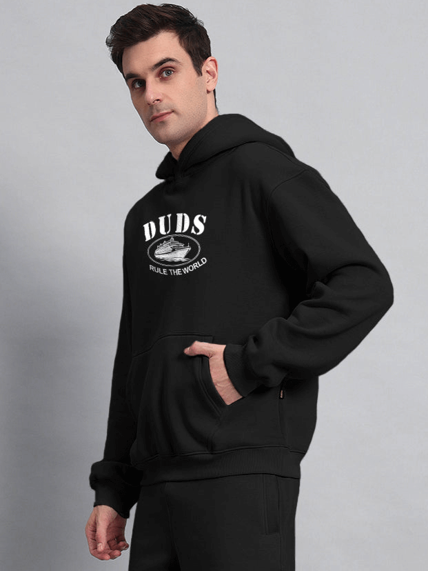 Man wearing RULE THE WORLD OVERSIZED HOODIE BLACK showing streetwear style in comfort and confidence.