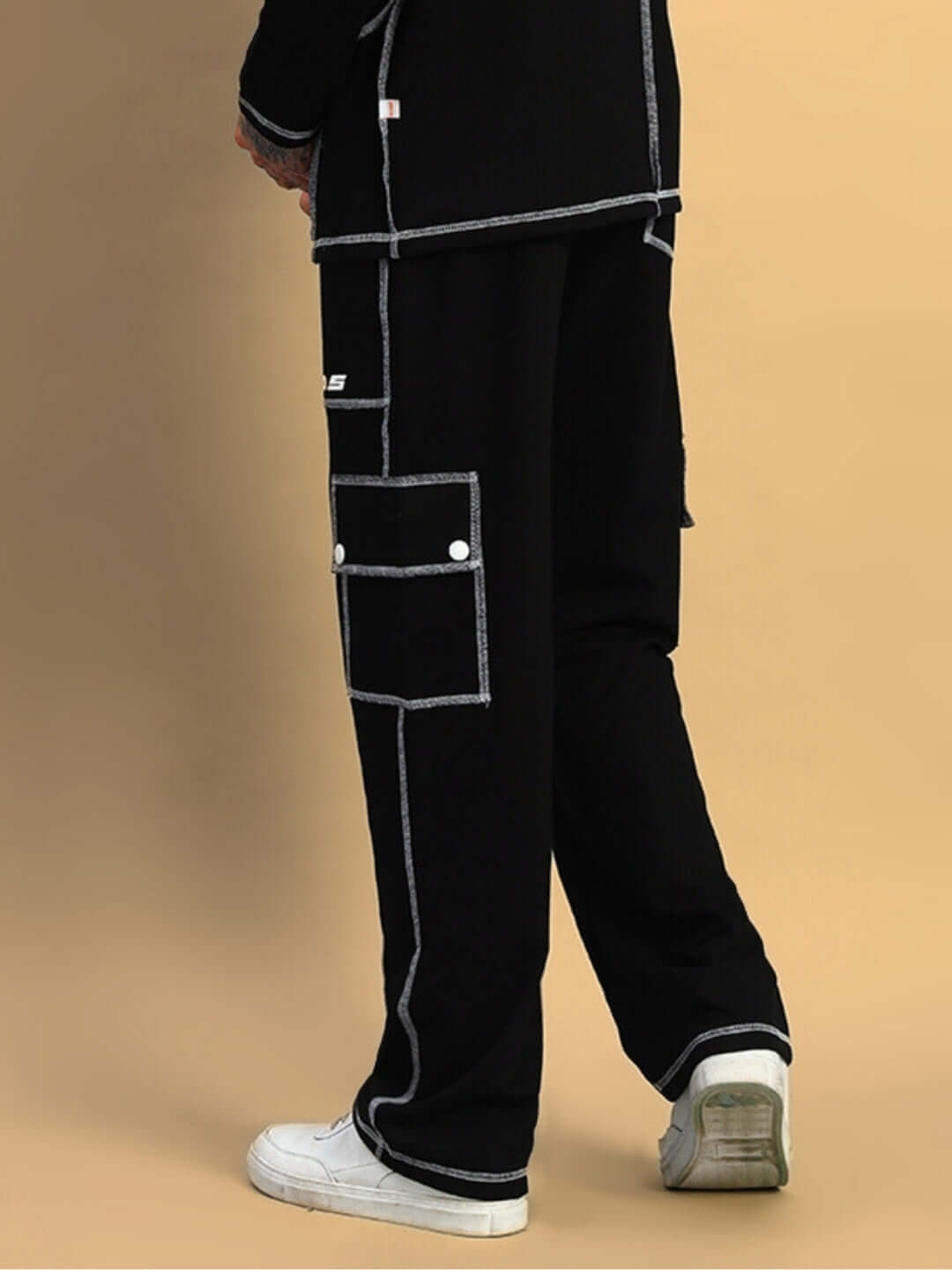 Back view of black dynamic 5 pocket cargo pant with white stitching, customizable fit option available, worn with white sneakers.
